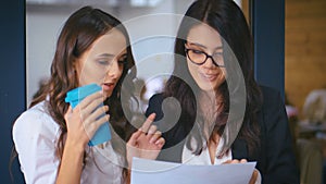 Two Young Businesswomen Confident managers discussing documents in office background. Female colleagues share ideas