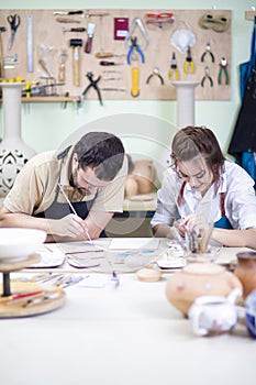Two Young Caucasian Ceramists Painting and Glazing Clay Crafts