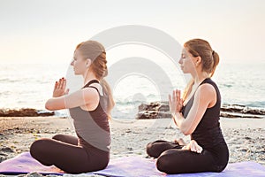 Two young caucasian females practicing yoga on beach