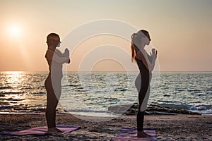 Two young caucasian females practicing yoga on beach