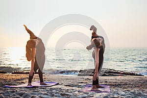 Two young caucasian females practicing yoga on beach