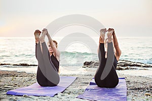 Two young caucasian females practicing yoga on beach