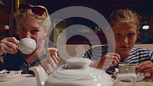 Two young caucasian girls drink tea and joke in cafe in evening after a hike