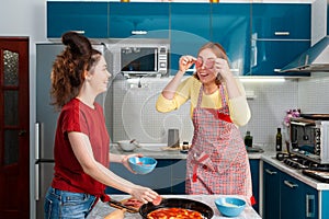 Two young Caucasian women cook pizza in the kitchen and have fun together. Indoors. Concept of joint home cooking for