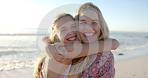 Two young Caucasian women embrace joyfully on a sunny beach