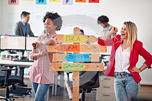 Two young cheerful female office worker are promoting company slogans while posing for a photo in the office. Employees, job,