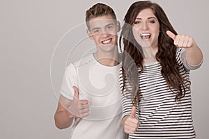 Two young cheerful people with thumbs up