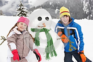 Two Young Children Building Snowman On Ski Holiday