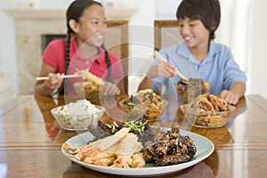 Two young children eating chinese food