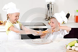 Two young children fighting over a rolling pin