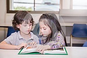 Two young children reading books at the school library