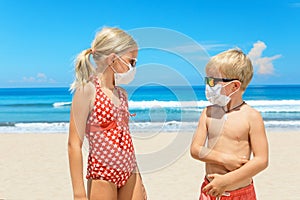 Two young children wearing sunglasses, protective mask on sea beach