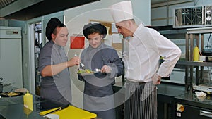 Two young cook trainees enjoying shrimp salad cooked by chef