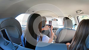 Two young couple traveling by car together. Men and women sitting in car`s interior during the road trip. Friends