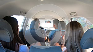Two young couple traveling by car together. Men and women sitting in car`s interior during the road trip. Friends