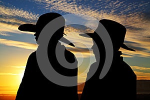 Two young cowboys silhouette wearing hats with a s