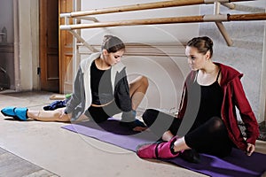 Two young cute ballerinas do stretching before training or rehearsal