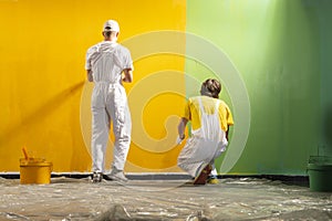 Two young decorators paint the wall