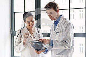 Two young dedicated doctors analyzing together a radiograph photo