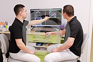 two young dentists are discussing and looking dental problems at x-ray image on computer screen. Healthy teeth and