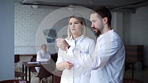 Two young dentists are examining the patient`s jaw X-ray.