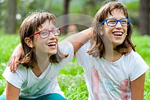 Two young disabled kids laughing outdoors.