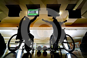 Two young disabled men in wheelchairs playing bowling in the club