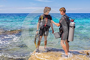 Two young divers check diving equipment in sea