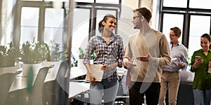 Two young diverse business people, male and female coworkers talking, discussing project and smiling while walking down