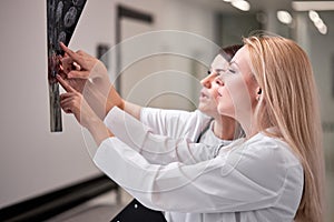 Two Young Doctors Looking At Computed Tomography X-ray Image, Discussing