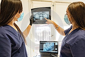 Two young doctors with masks are looking at the X-ray