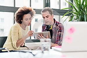 Two young employees watching a video on tablet PC in the office