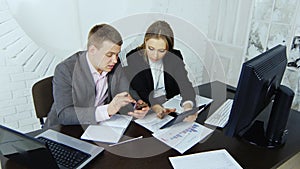 Two young enterprising business partners work on a tablet in a study on the background of a round window