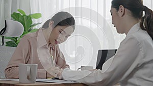 Two young enthusiastic businesswoman working together in the office workspace.