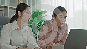 Two young enthusiastic businesswoman working together in the office workspace.