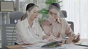 Two young enthusiastic businesswoman working together in the office workspace.