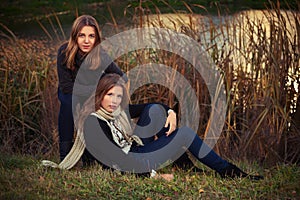 Two young fashion girls in black pullover and dark blue jeans outdoor