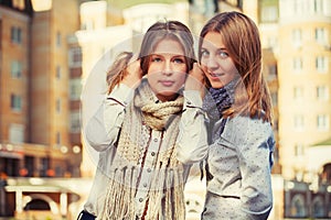 Two young fashion girls in white shirt and scarf walking in city street