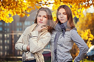 Two young fashion girls in white shirt and scarf walking in city street