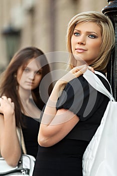 Two young fashion women with handbag on city street