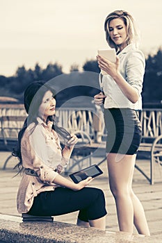 Two young fashion women using digital tablet computer