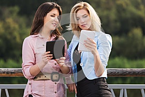 Two young fashion women using tablet computer