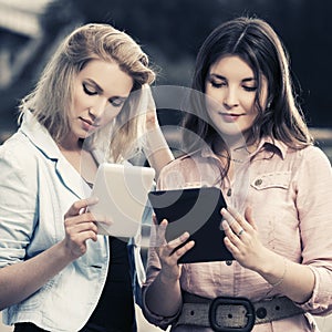 Two young fashion women using tablet computer outdoor