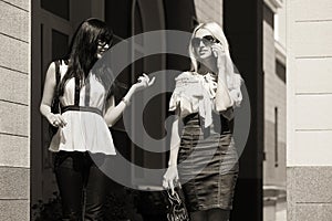 Two young fashion women walking in city street