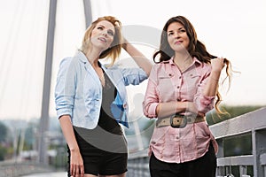 Two young fashion women walking on city street