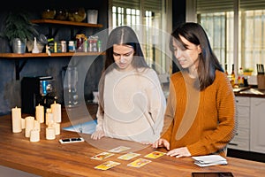 Two young femaies nervous about using tarot cards in a family kitchen