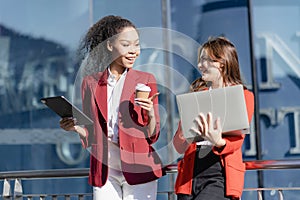 Two young female accountants walk and talk in front of the building\'s office.