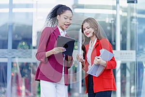 Two young female accountants walk and talk in front of the building\'s office.