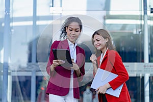 Two young female accountants walk and talk in front of the building\'s office.