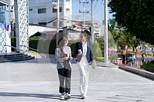 Two young female accountants walk and talk in front of the building\'s office.